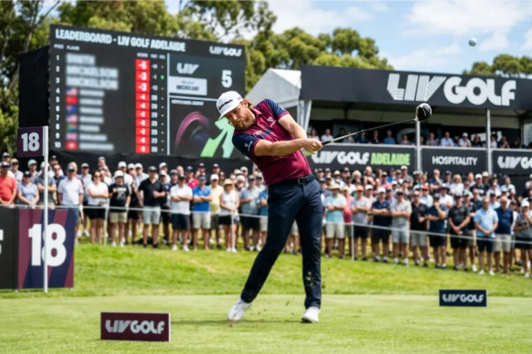 Golfista profesional ejecutando un golpe de salida en un torneo LIV Golf con público al fondo y equipamiento de competición